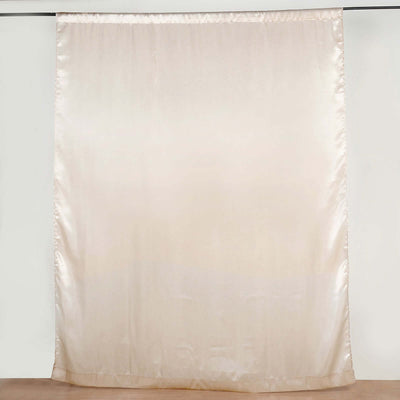 Beige silk curtain hanging from a rod against a plain backdrop