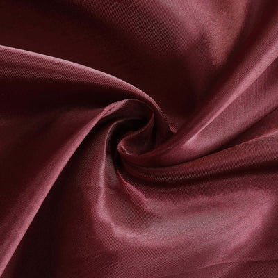 Burgundy satin fabric swirl texture close-up.