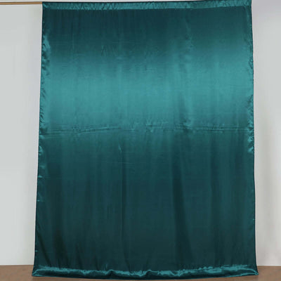 Teal satin fabric draped elegantly on a plain backdrop.