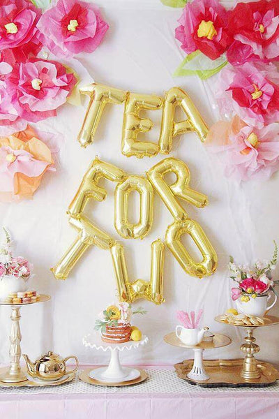 Gold "Tea for Two" balloons with floral decorations for a celebration.