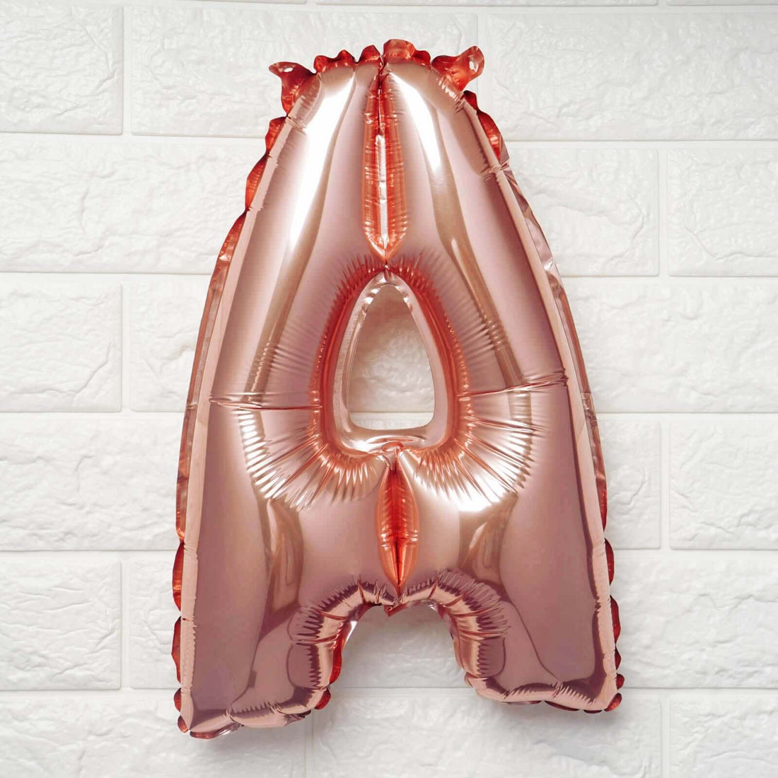 Rose gold letter A foil balloon against a white background