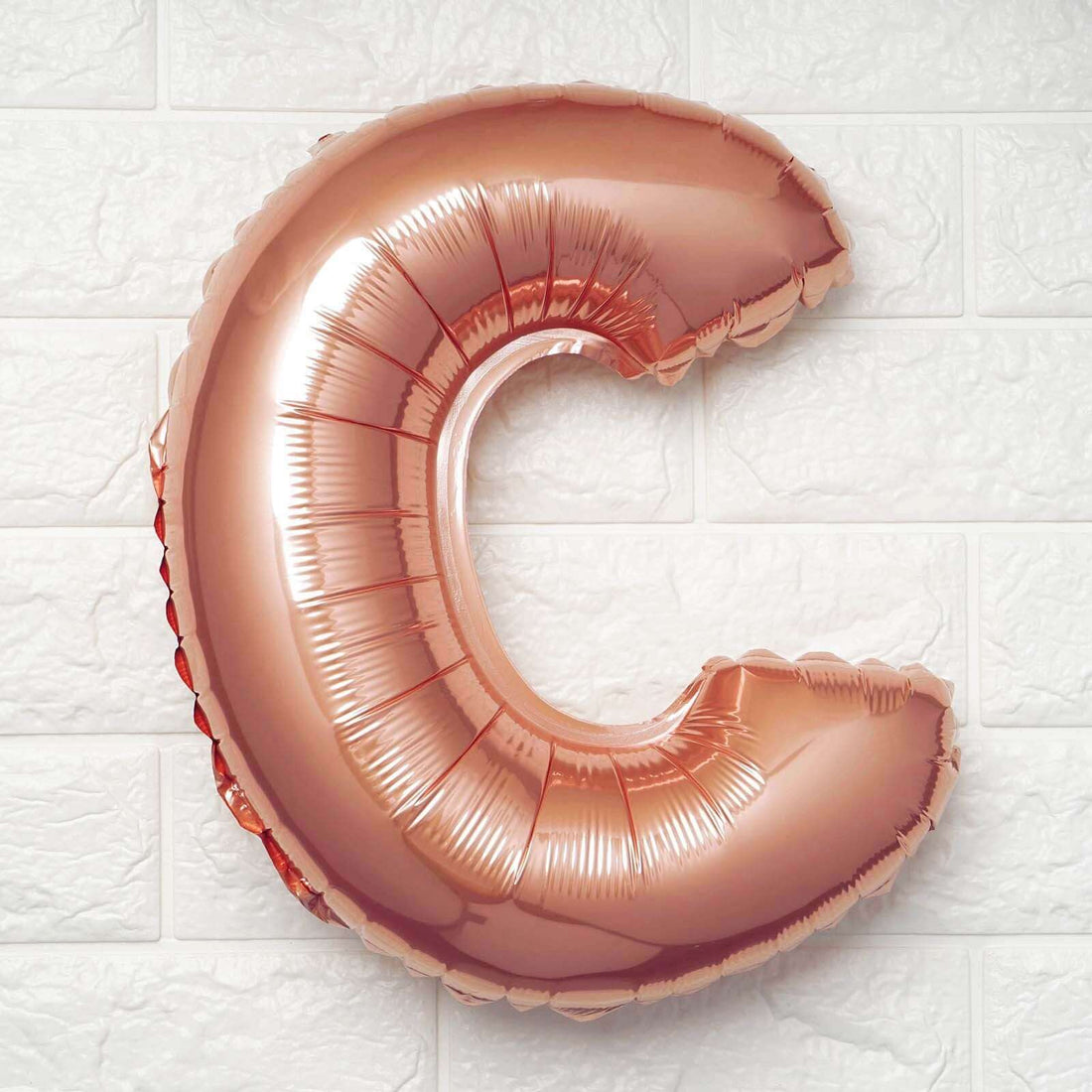 Rose gold letter C balloon on a white background