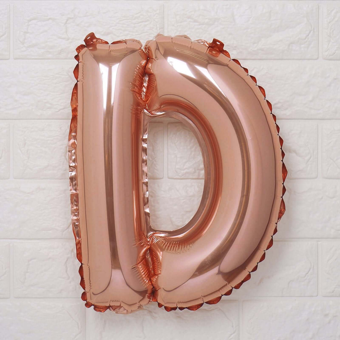 Rose gold foil letter D balloon on a white background.