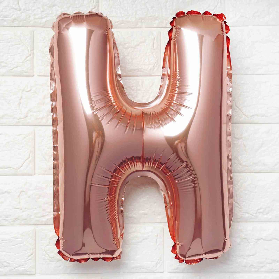 Rose gold letter H balloon on a white background.
