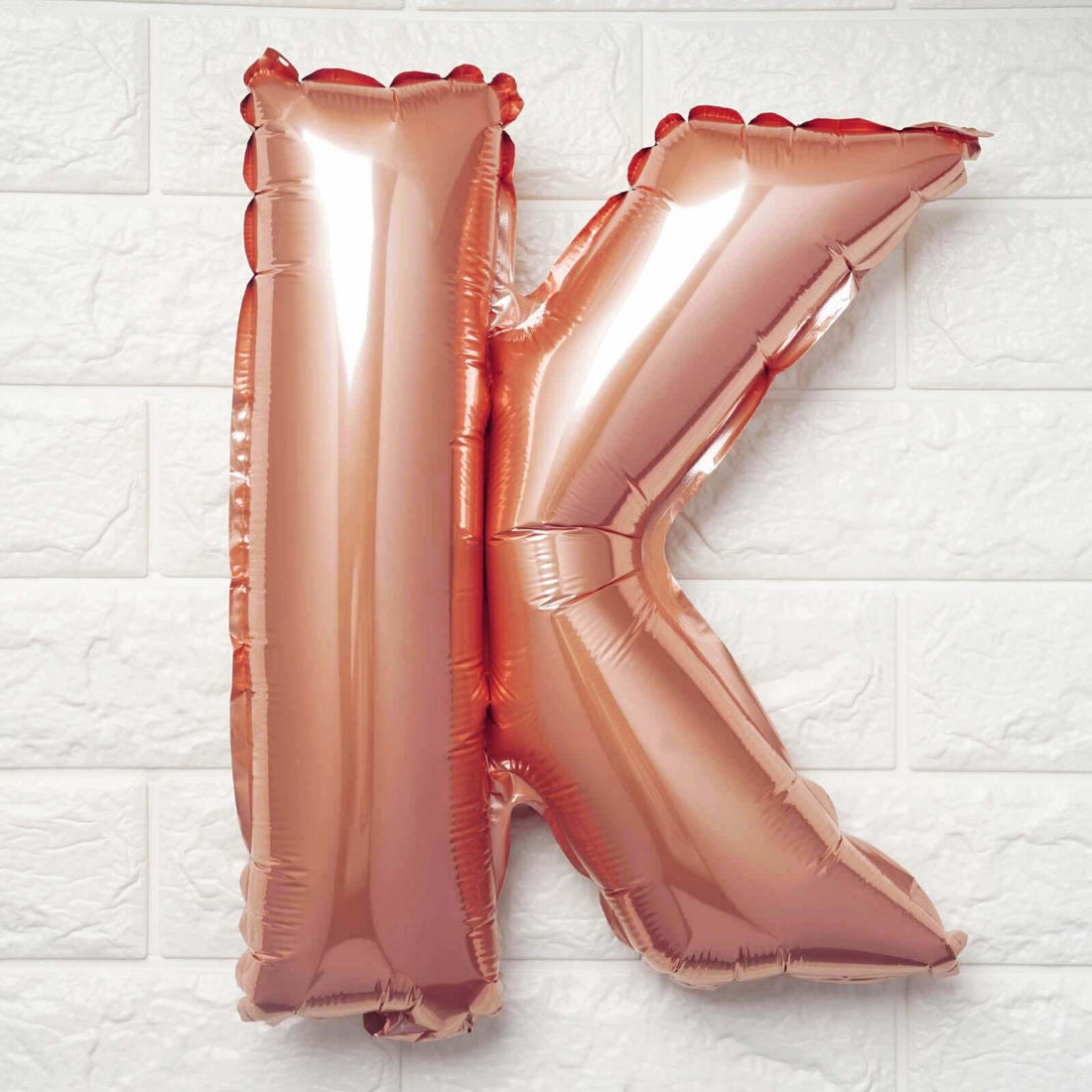 Rose gold foil letter K balloon on white background