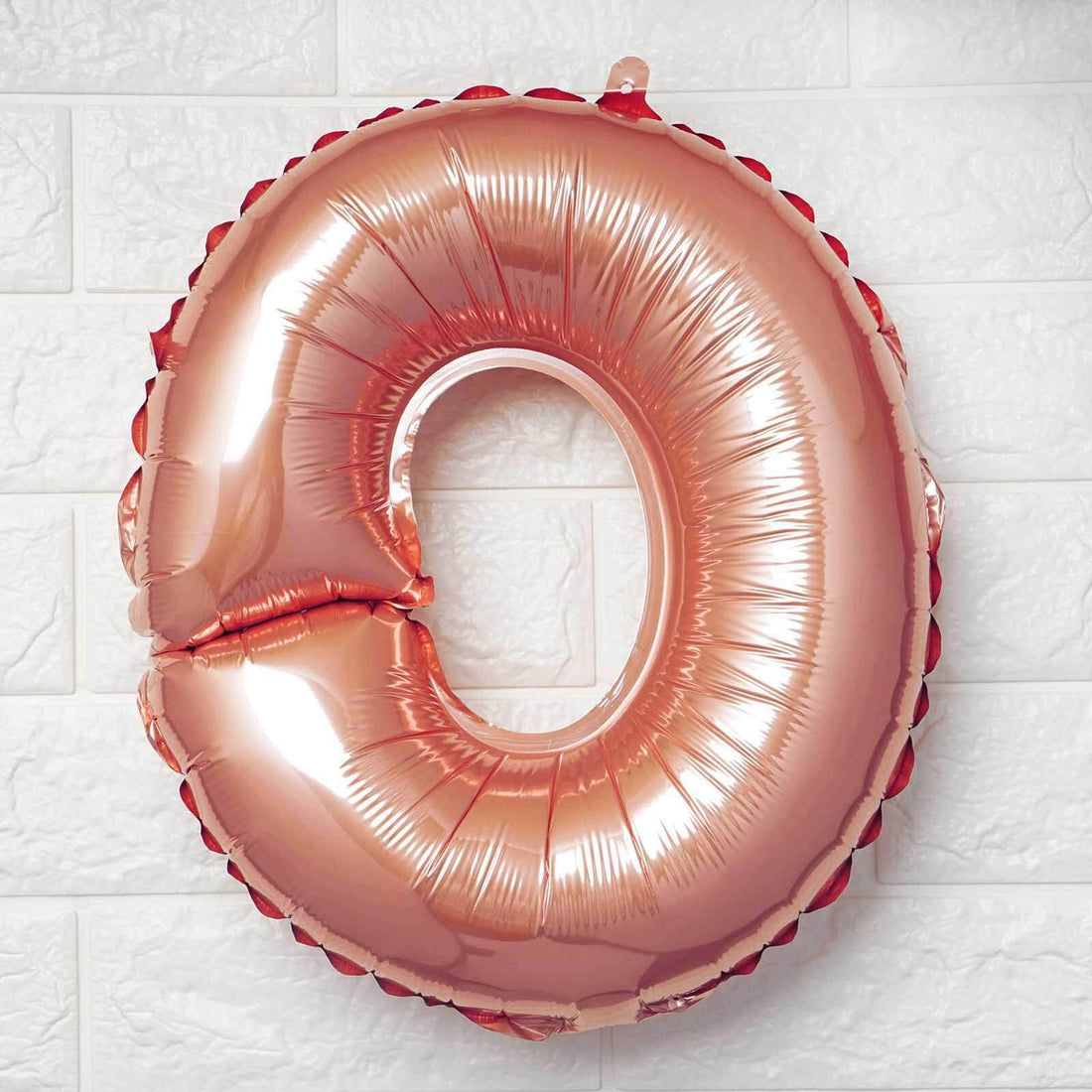 Rose gold number 0 balloon on a white background.