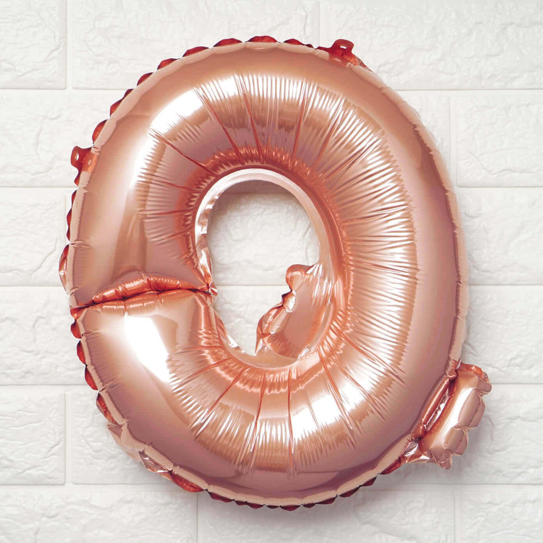Rose gold number 0 balloon on a textured white background.