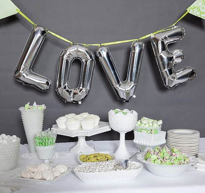 Silver "LOVE" balloons with white desserts on a table.