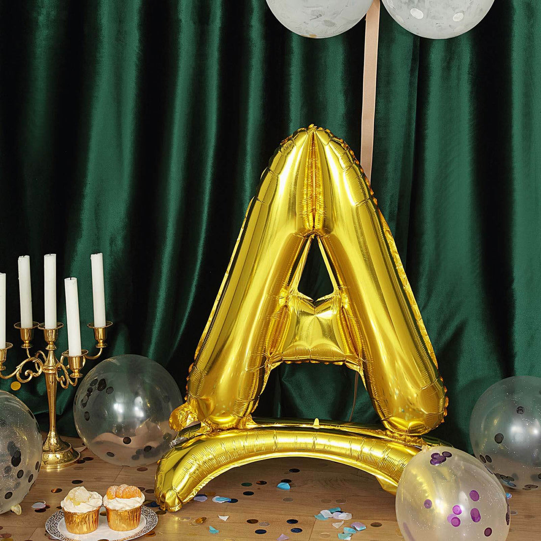 Golden letter A balloon surrounded by cupcakes and party decorations. #whtbkgd