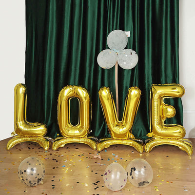 Gold "LOVE" balloon decoration with confetti and balloons on the floor.