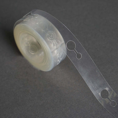 Transparent adhesive tape roll on a dark surface.
