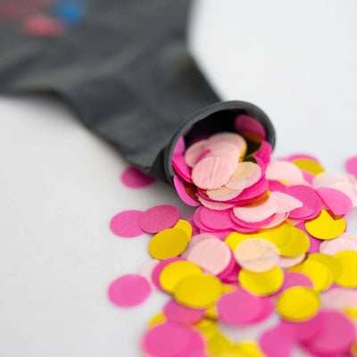 Colorful confetti spilling from a black balloon on a white background.