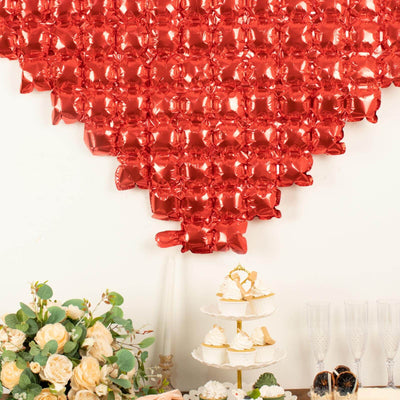 Red heart-shaped balloon backdrop with desserts and floral arrangement.