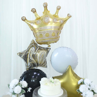 Gold crown and star balloons with white and black accents, arranged for a celebration.