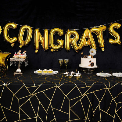 Gold "CONGRATS" balloon banner at a festive table with cake and treats.