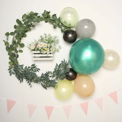 Decorative wall arrangement with balloons, greenery, and flowers in a white planter.