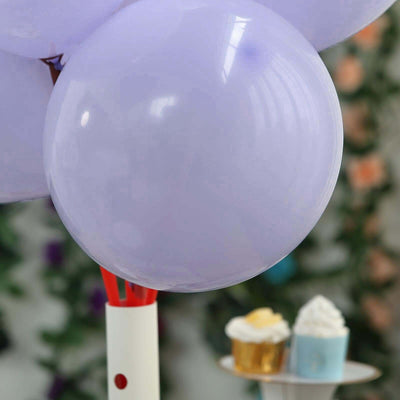 Purple balloon on a stand with cupcakes in the background.