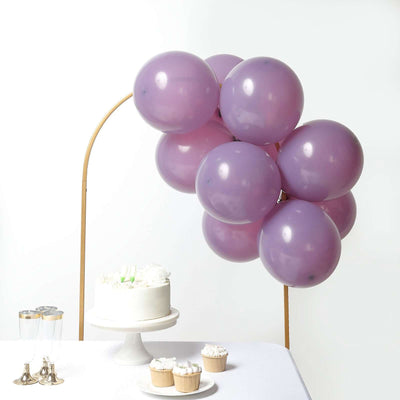 Purple balloons arranged over a cake and cupcakes on a white table.