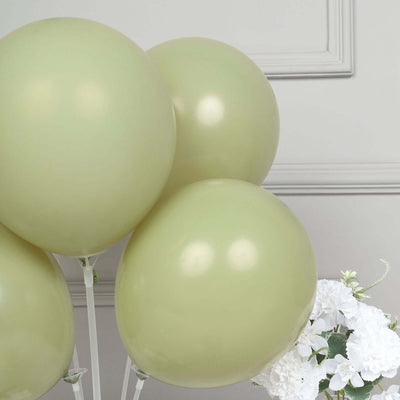 Green balloons clustered together with white flowers in the background.