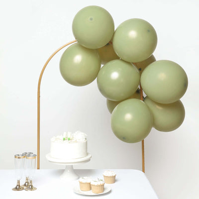 Green balloons arching over a cake and cupcakes on a table.