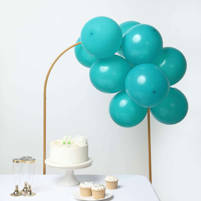 Teal balloons and a cake with cupcakes on a table
