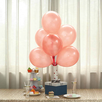 Pink balloons arranged in a decorative display with a gift box and treats.