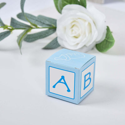 Blue baby block with letters A and B, surrounded by greenery and a white rose.