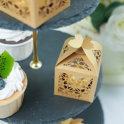 Gold decorative gift box with intricate cutout design on a tiered dessert stand.