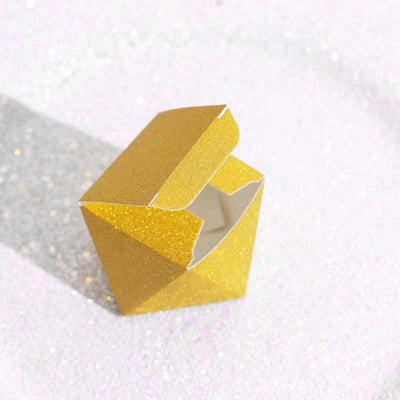 Gold glitter gift box with an open lid on a sparkling background.