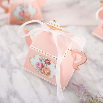 Pink tea pot favor box with floral design and ribbon.