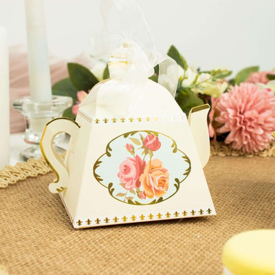Decorative floral teapot favor box with ribbon and gold accents.