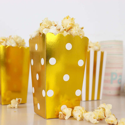 Gold polka dot popcorn boxes filled with popcorn on a white background.