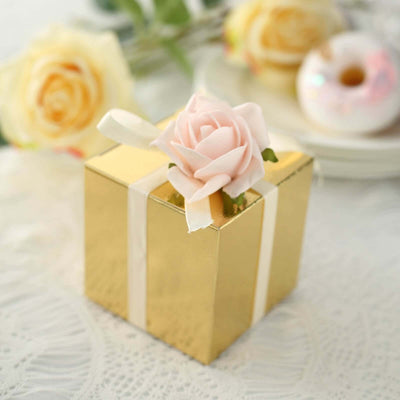 Gold gift box adorned with a pink rose on a lace tablecloth.