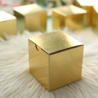 Shiny gold gift box with a textured surface on a fluffy background.