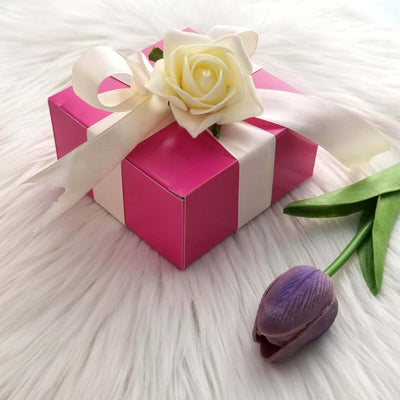 Pink gift box with a white ribbon and rose on a fluffy background.