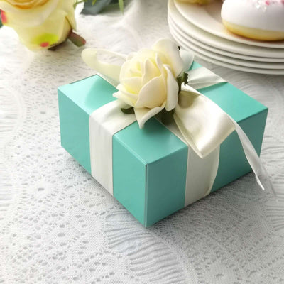 Elegant mint green gift box adorned with a white ribbon and floral decoration.