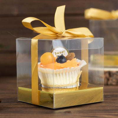 Transparent gift box with a cupcake, adorned with a golden ribbon.