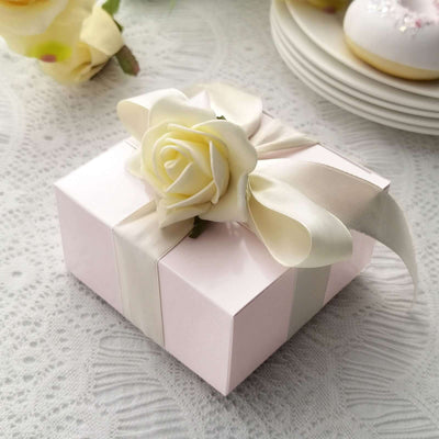 Pink gift box adorned with a white rose and ribbon on a lace tablecloth.