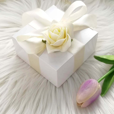 White gift box with ribbon and flower on faux fur background.