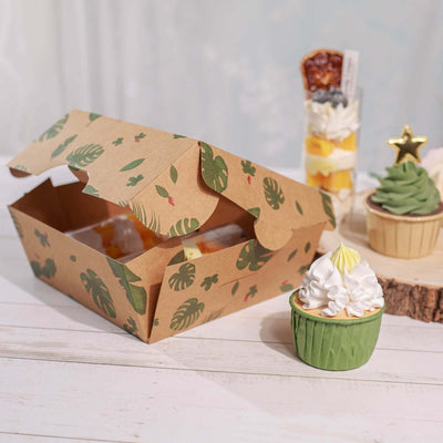 Cupcake with cream frosting beside a decorated dessert box.