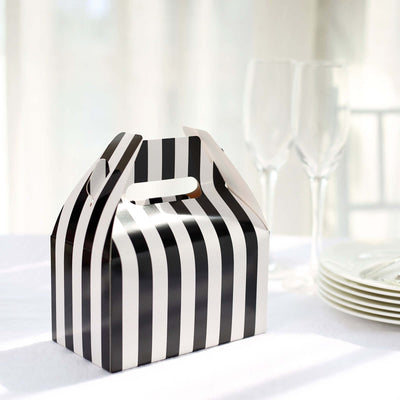 Black and white striped gift box on a table with glasses and plates.