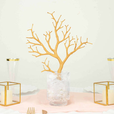 Gold branch centerpiece in a clear vase with ice, elegantly styled for dining table.