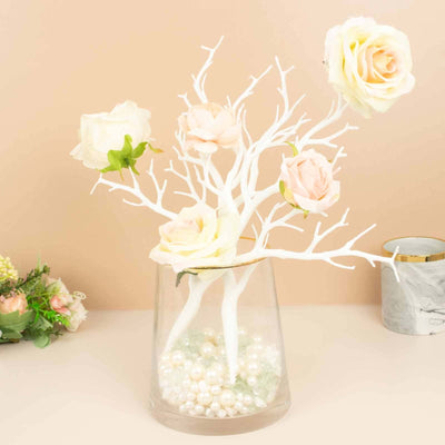 White floral arrangement with pastel roses in a clear glass vase.