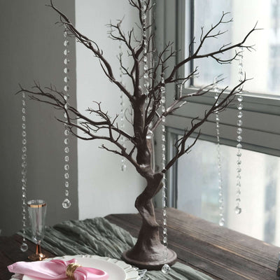 Decorative tree centerpiece with hanging crystals on a dining table.