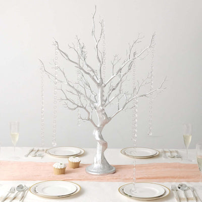 Silver decorative tree centerpiece with hanging crystals on a dining table.