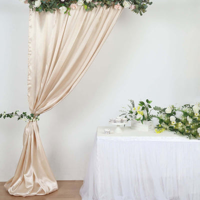Elegant cream drapery with floral decor and a decorated table for an event setup.