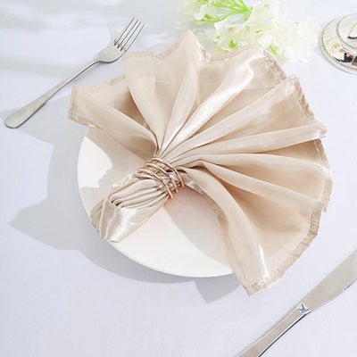 Elegant beige satin napkin elegantly arranged on a white plate.
