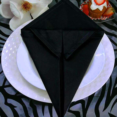 Black napkin elegantly folded on a white plate with decorative background.