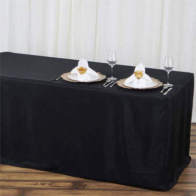 Black tablecloth draped over a table set for dining with elegant napkins and glassware.
