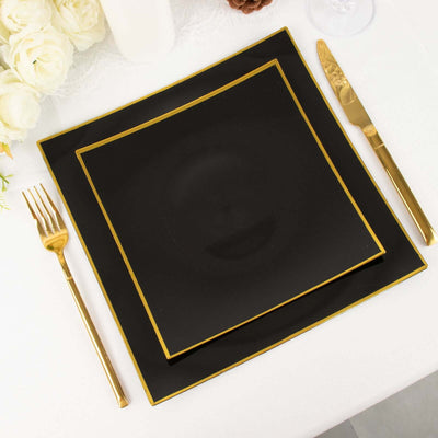 Black plates with gold trim set on a table with gold cutlery.